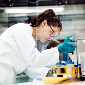 Female researcher uses pipette to move solution from one test tube to another in lab